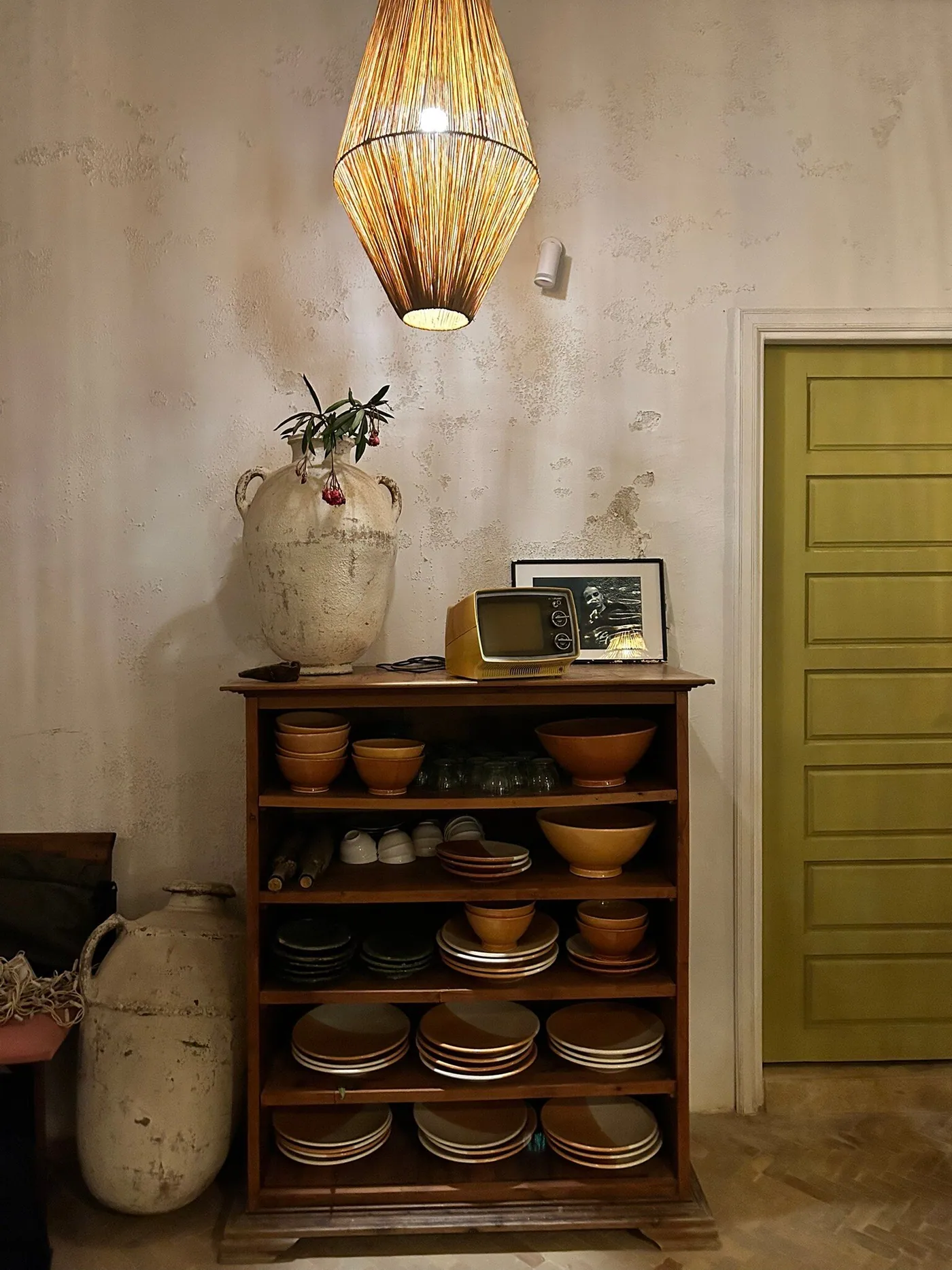 Shelf of handmade ceramic bowls and a woven lamp