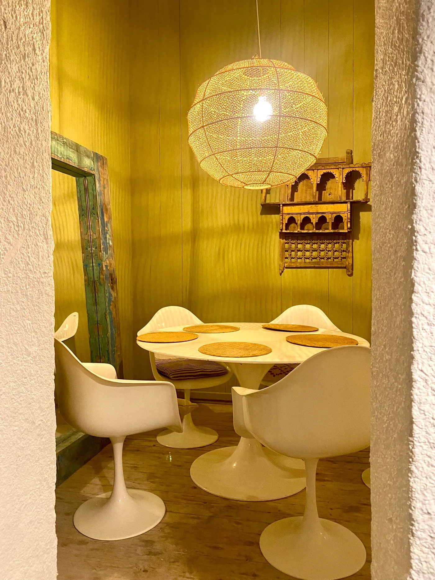 Saffron-yellow dining nook with white tulip table and chairs